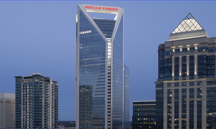 A nighttime skyline of Charlotte, North Carolina, showing the Wells Fargo signage.