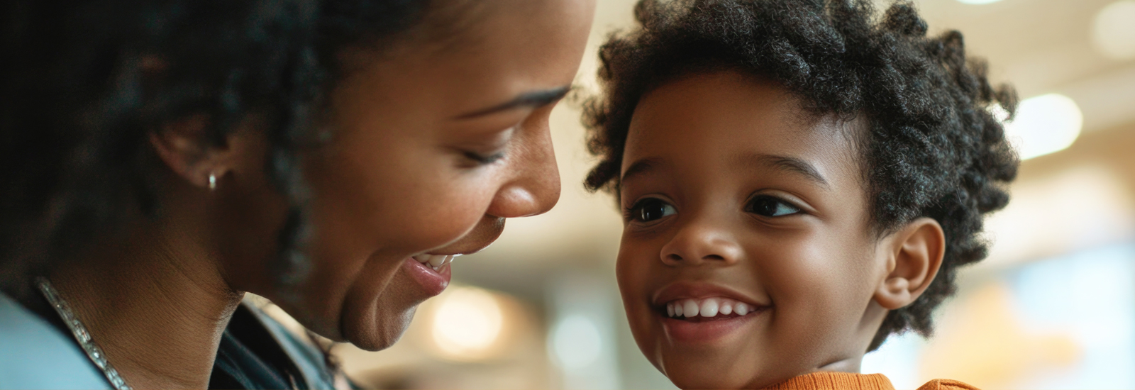 A woman and a young child smile at each other.