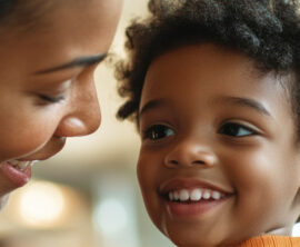 A woman and a young child smile at each other.