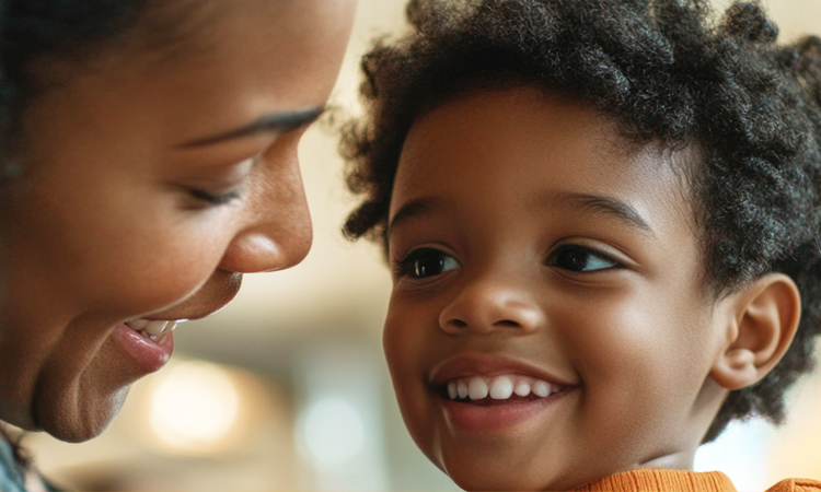 A woman and a young child smile at each other.