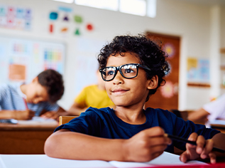 A child sits at a desk in a classroom.