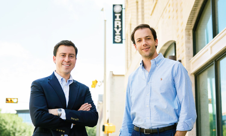 Two people stand outside a brick office building with an Irys sign visible in the background.