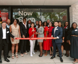 A group of community leaders and Wells Fargo representatives stand outside a branch during a ribbon-cutting ceremony.