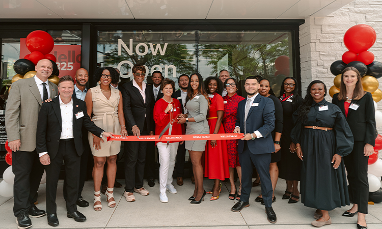 A group of community leaders and Wells Fargo representatives stand outside a branch during a ribbon-cutting ceremony.