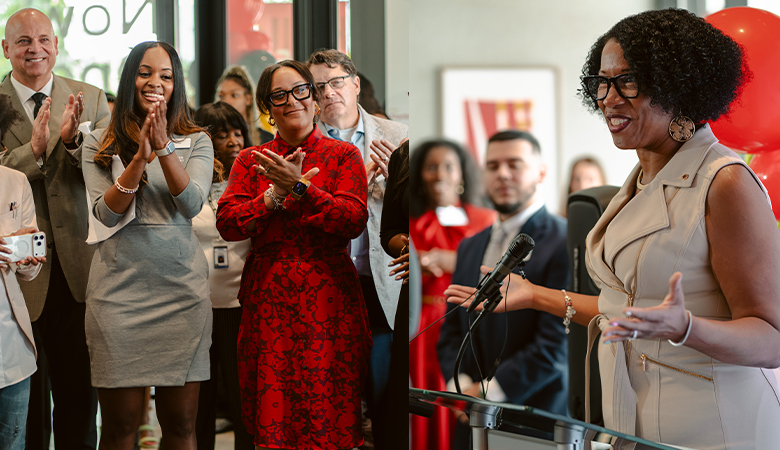 A speaker addresses attendees during a community event as audience members applaud.