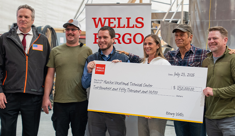 Five people smile as they stand behind an oversized check for $250,000