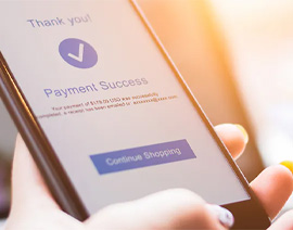 A close-up of a hand holding a phone. On the screen is a message saying Thank you, Payment Success with a blue circle and a white check mark.