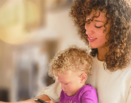 A woman sits looking down at a child in her lap.