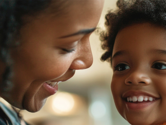A woman smiles down at a small child.