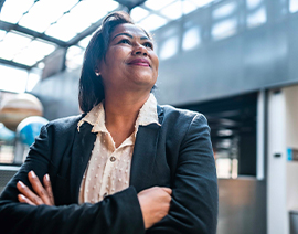 A woman stands with her arms crossed staring up.
