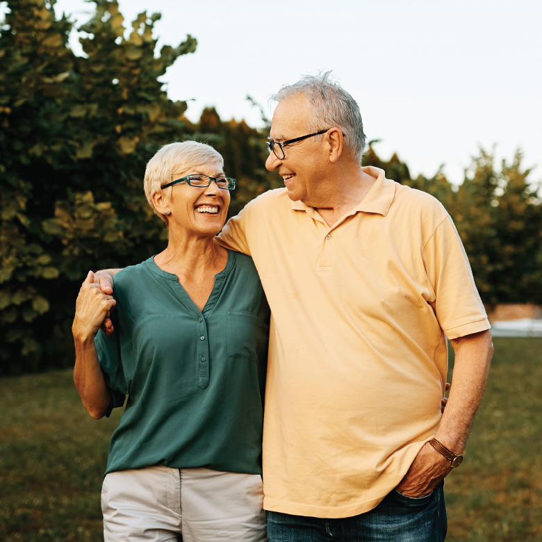 Two older adults walk together in an embrace