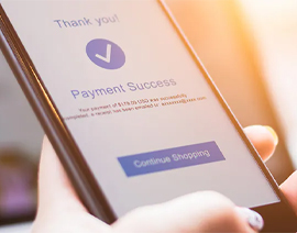 A hand holding a phone showing a "payment successful" screen.