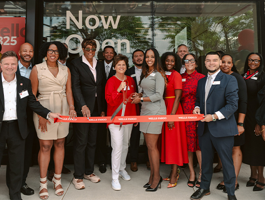 A group of people attend a ribbon cutting for a Wells Fargo branch opening.