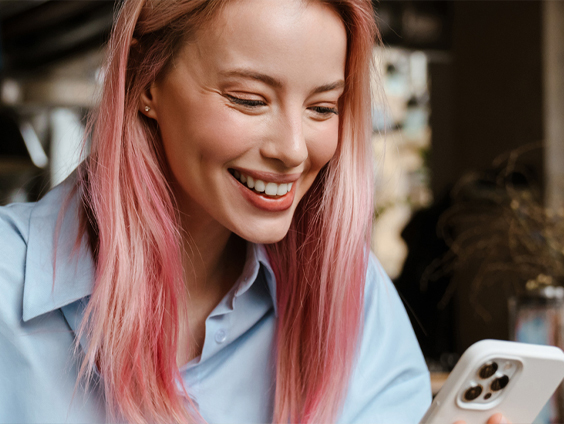 A woman smiles while looking down at her phone