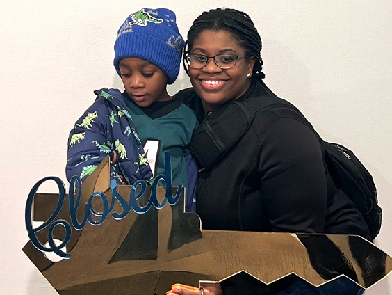 A woman and her child hold an oversized key with the word "Closed"