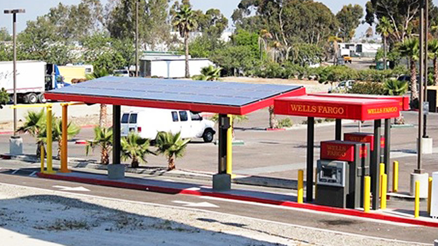 A Wells Fargo ATM is powered by a large solar panel adjacent to it.