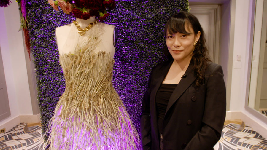 Designer Michelle Hébert stands next to a gown on a mannequin.