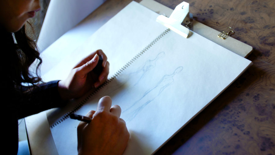 Photo of Michelle Hébert’s hands as she sketches designs.