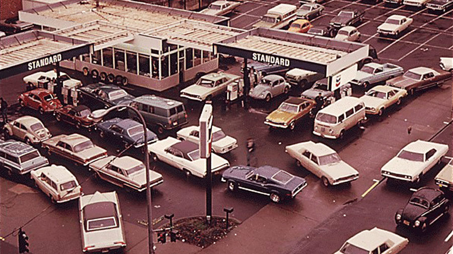 A color photograph showing the aerial view of lines of cars at a gas station.