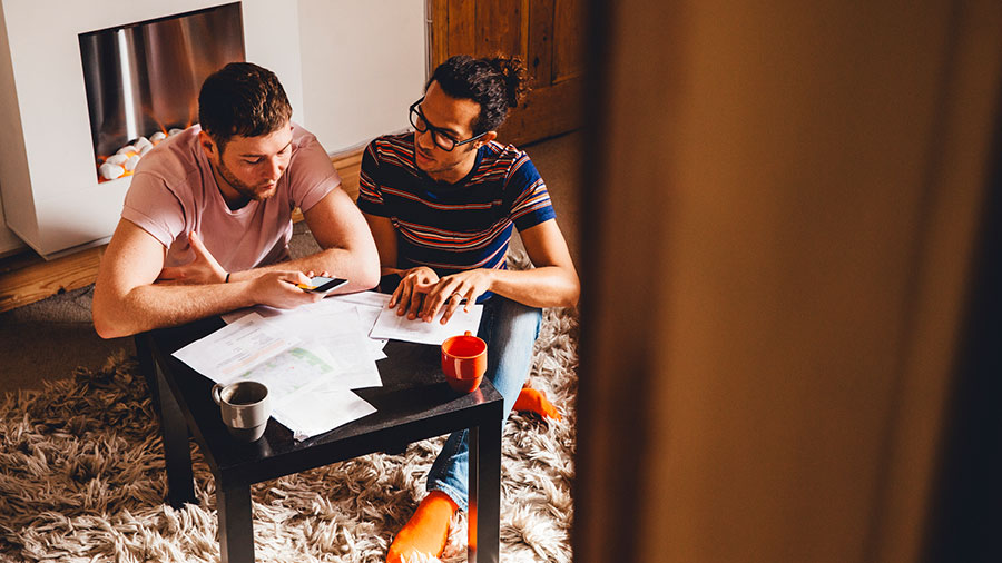 Una pareja se sienta en una mesa en su habitación familiar y habla sobre sus finanzas.