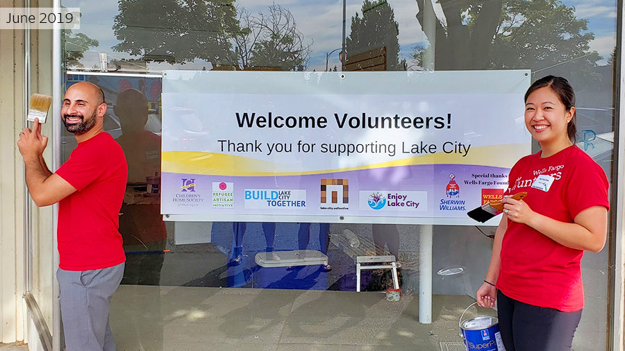 Two Wells Fargo employees in red Wells Fargo Volunteer T-shirts pause with their brushes before the 