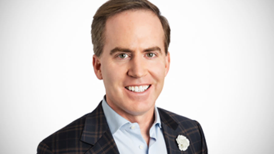 Nate Hurst’s headshot shows him smiling at the camera and wearing a dark blazer over a light blue collared shirt.