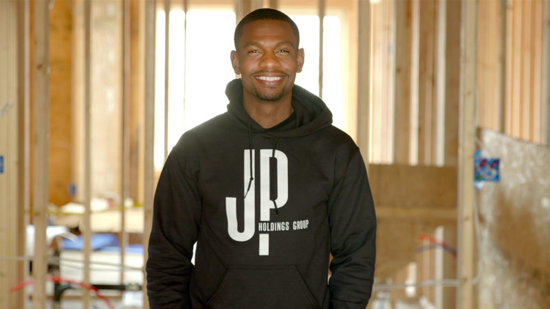 Patrick Jeune is smiling and standing in a building that is under construction.