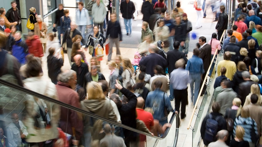 Large numbers of holiday shoppers enter and leave a crowded store.