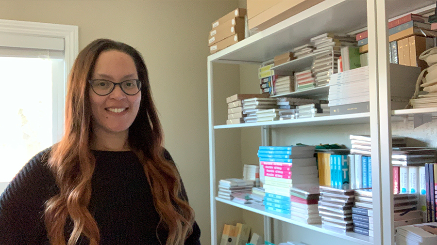 Valli Hilaire smiles and stands next to a shelf with stacks of paper products.