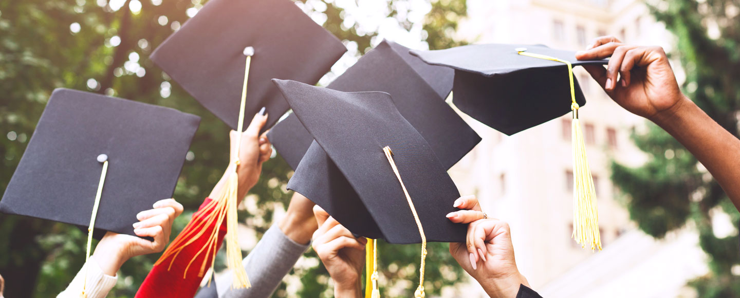 Graduates raise black caps and tassels in the air